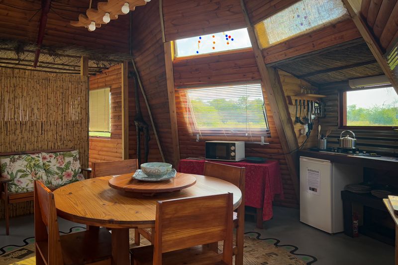 A cozy wooden cabin interior featuring a dining area, kitchenette, and rustic decor.