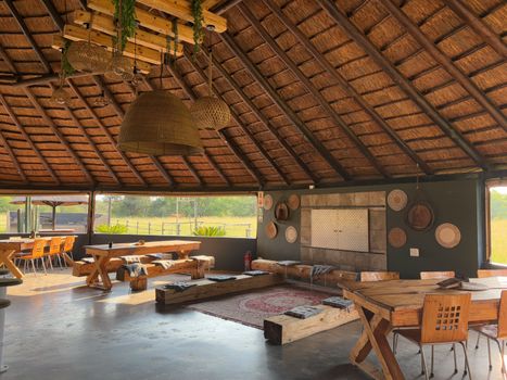 Cozy open-air dining area with a thatched roof and rustic wooden furniture.