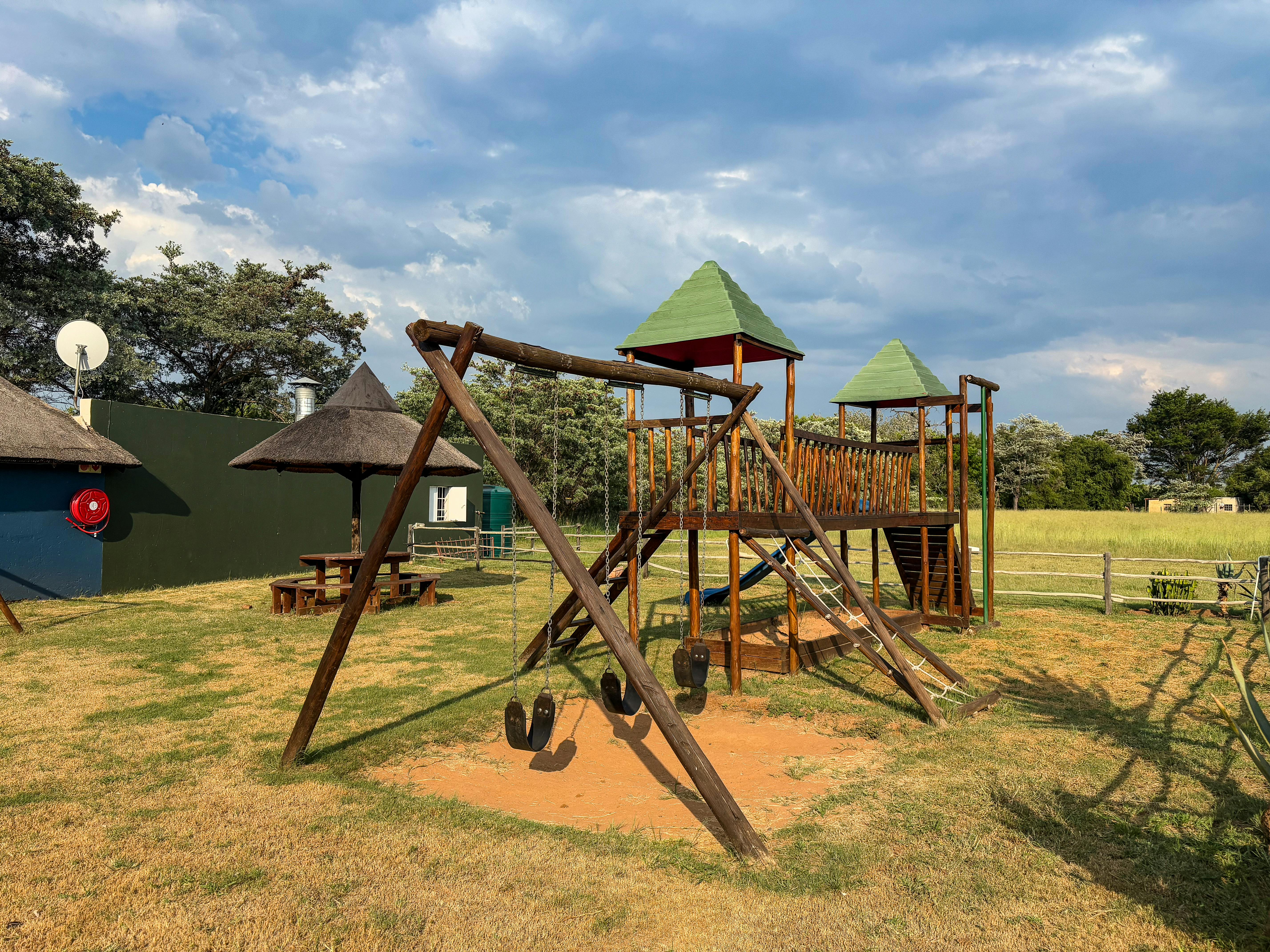 Empty wooden playground outdoors under sunny skies, ideal for kids' activities.