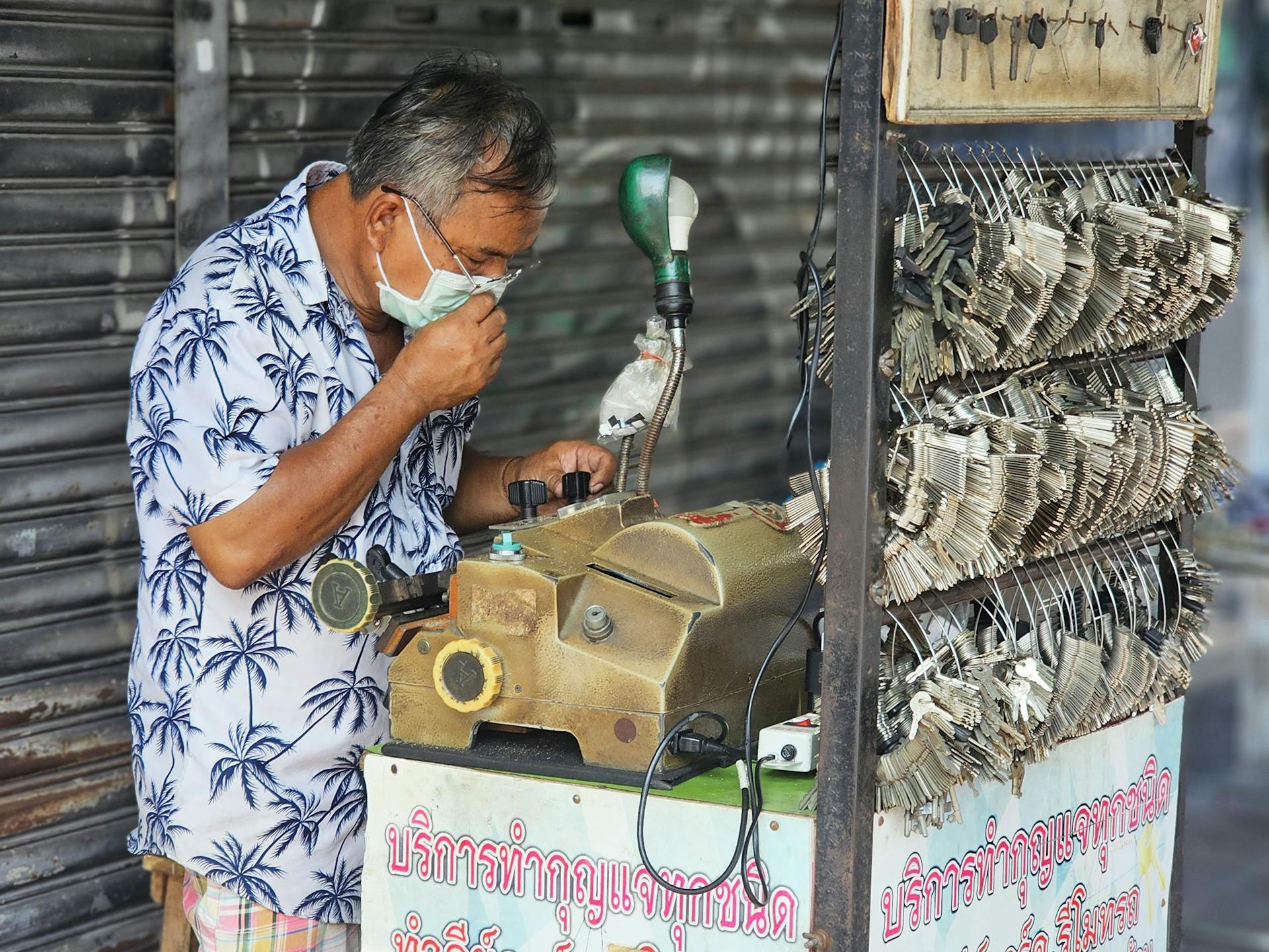 Asian locksmith operates a mobile key machine outdoors. Hardware business scene.