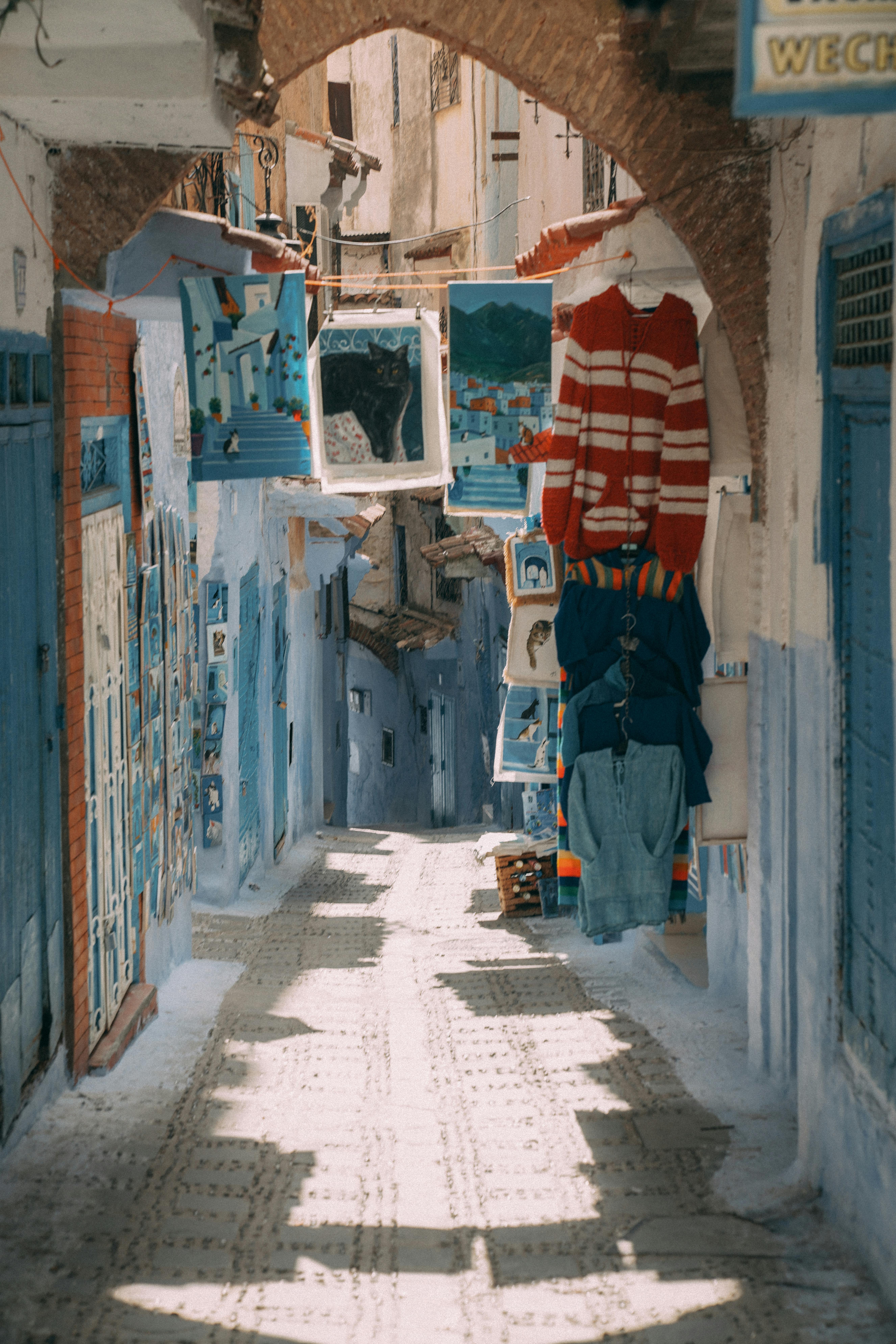 Explore the vibrant blue streets of Chefchaouen, Morocco, adorned with colorful textiles and art.
