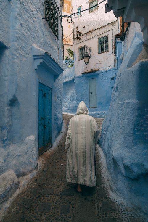 Free Person walking through the iconic blue streets of Chefchaouen, Morocco. Stock Photo