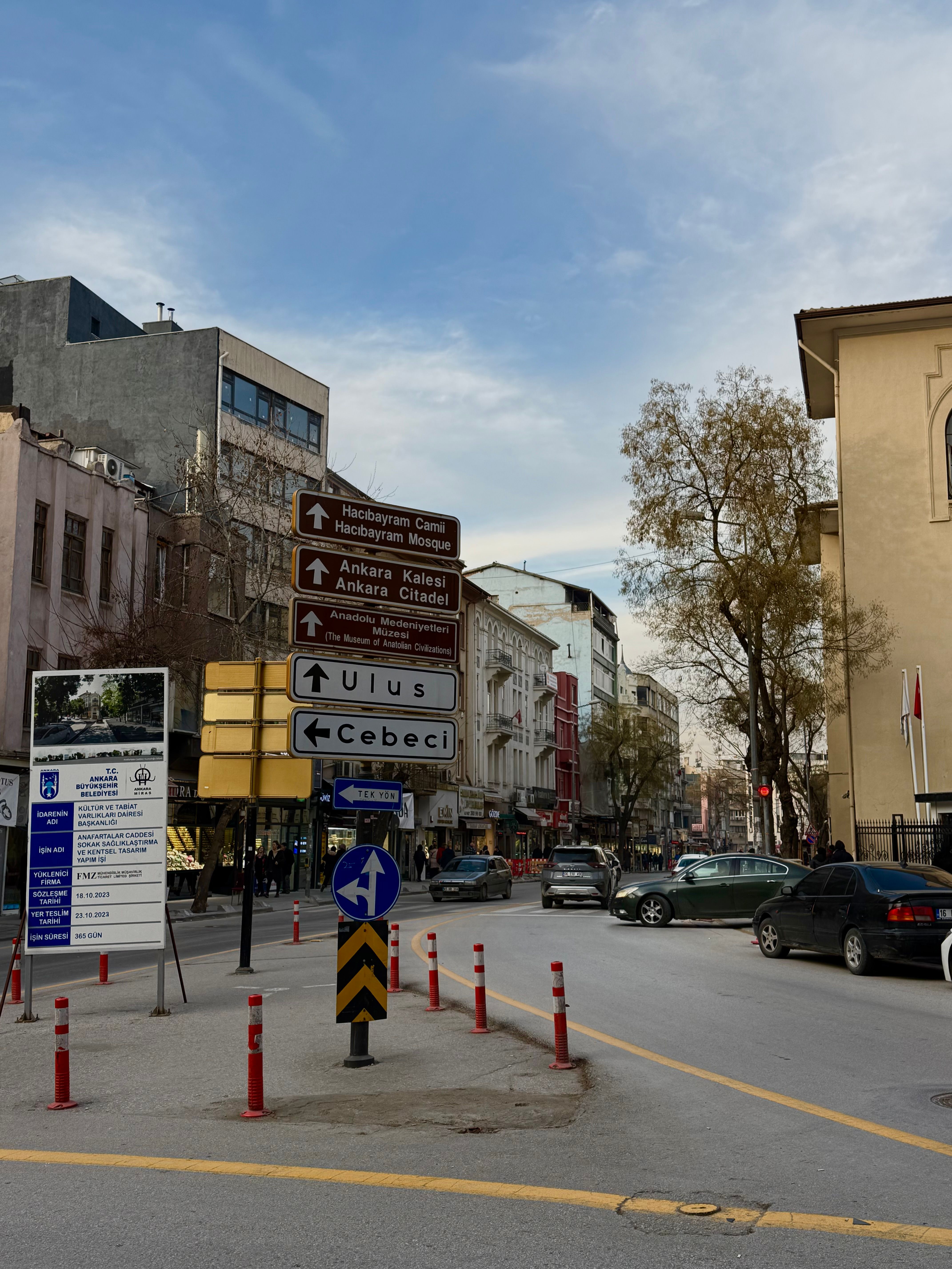 Urban street scene in Ankara featuring directional signs and city buildings.