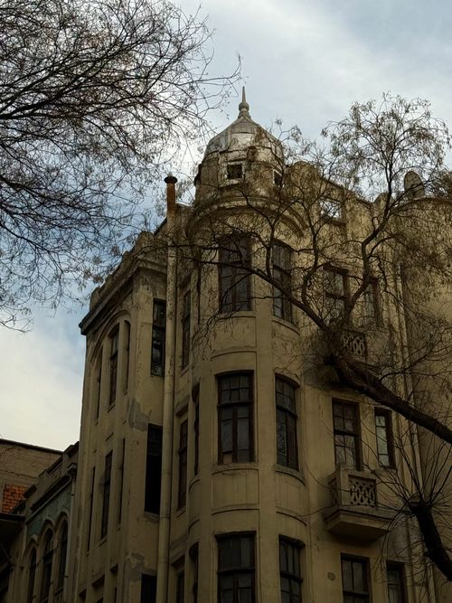 Free A vintage European building with intricate architectural details surrounded by barren trees. Stock Photo