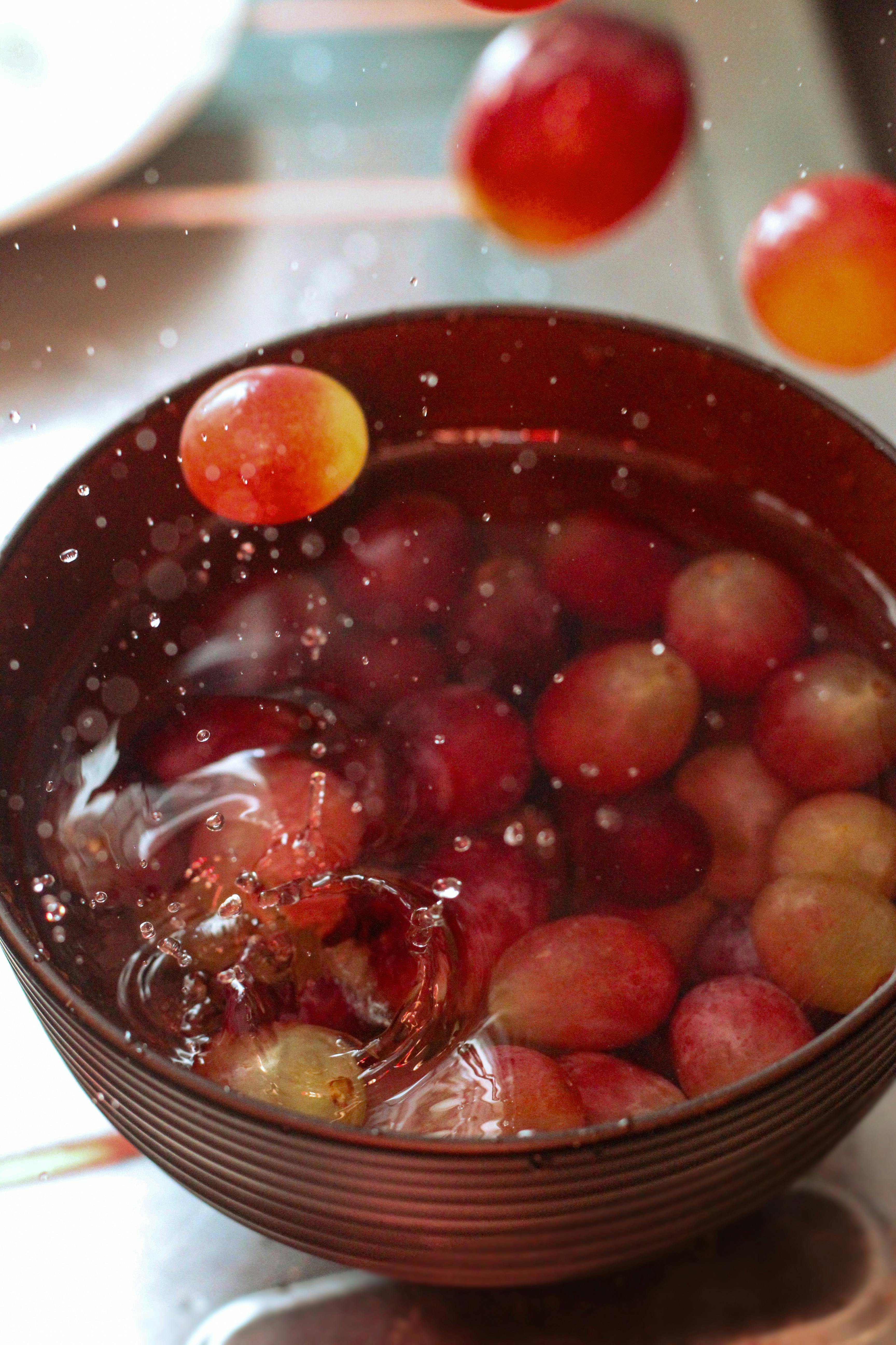Ripe red grapes splashing into a bowl of water, emphasizing freshness and vibrant energy.