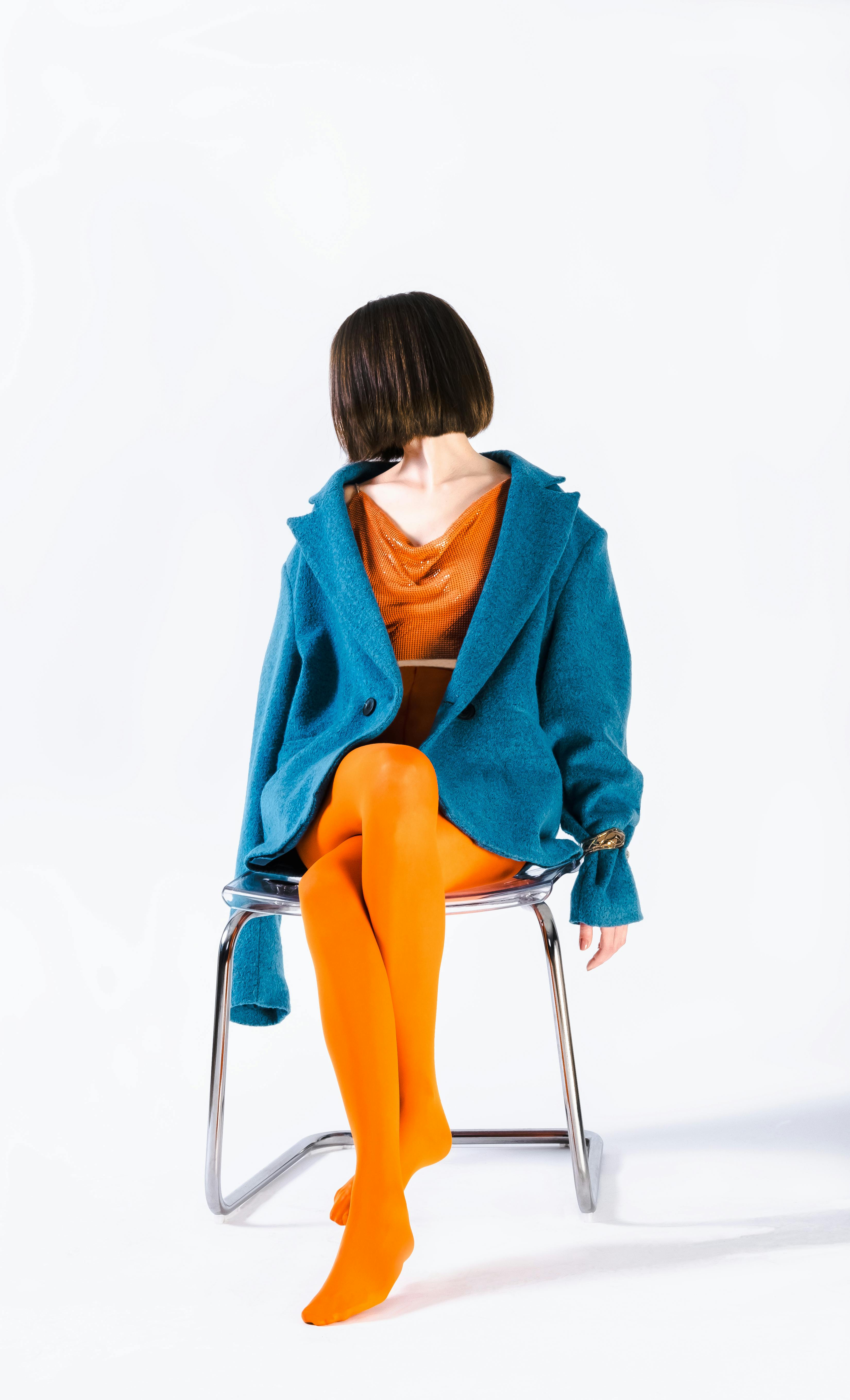 Striking fashion photo showcasing vibrant blue and orange outfit on seated model.