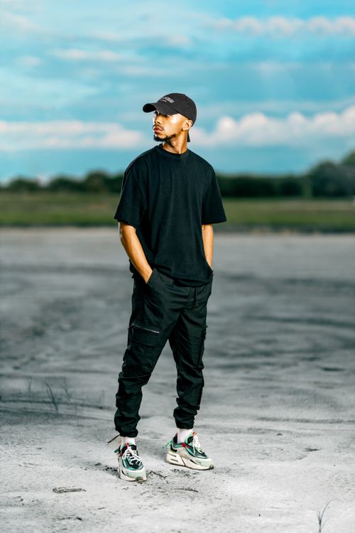 Free Man in casual style standing outdoors, hands in pockets, bright day. Stock Photo