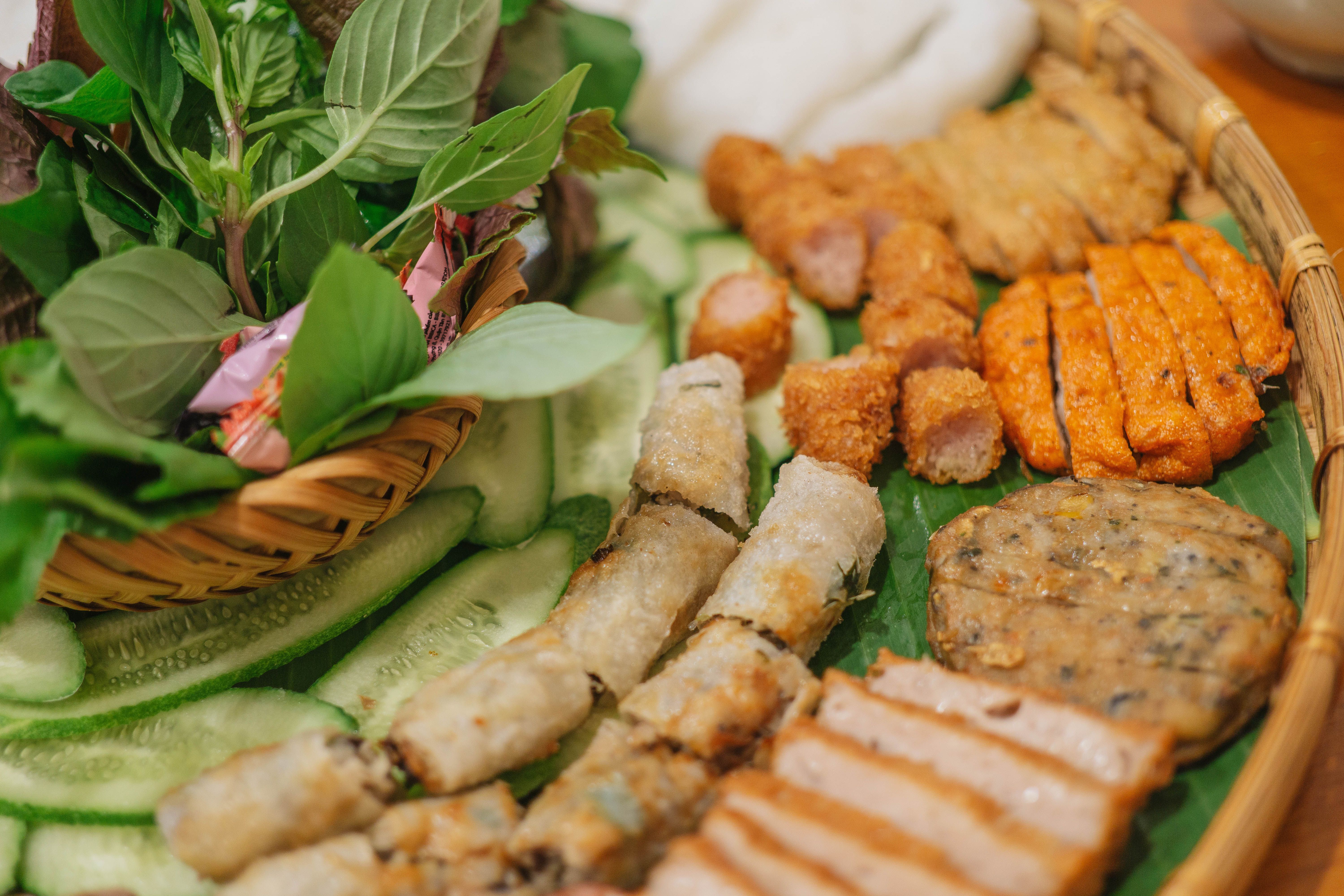 Miễn phí Một đĩa thức ăn Việt Nam đầy màu sắc với các loại thảo mộc tươi, chả giò và thịt nướng. Ảnh lưu trữ