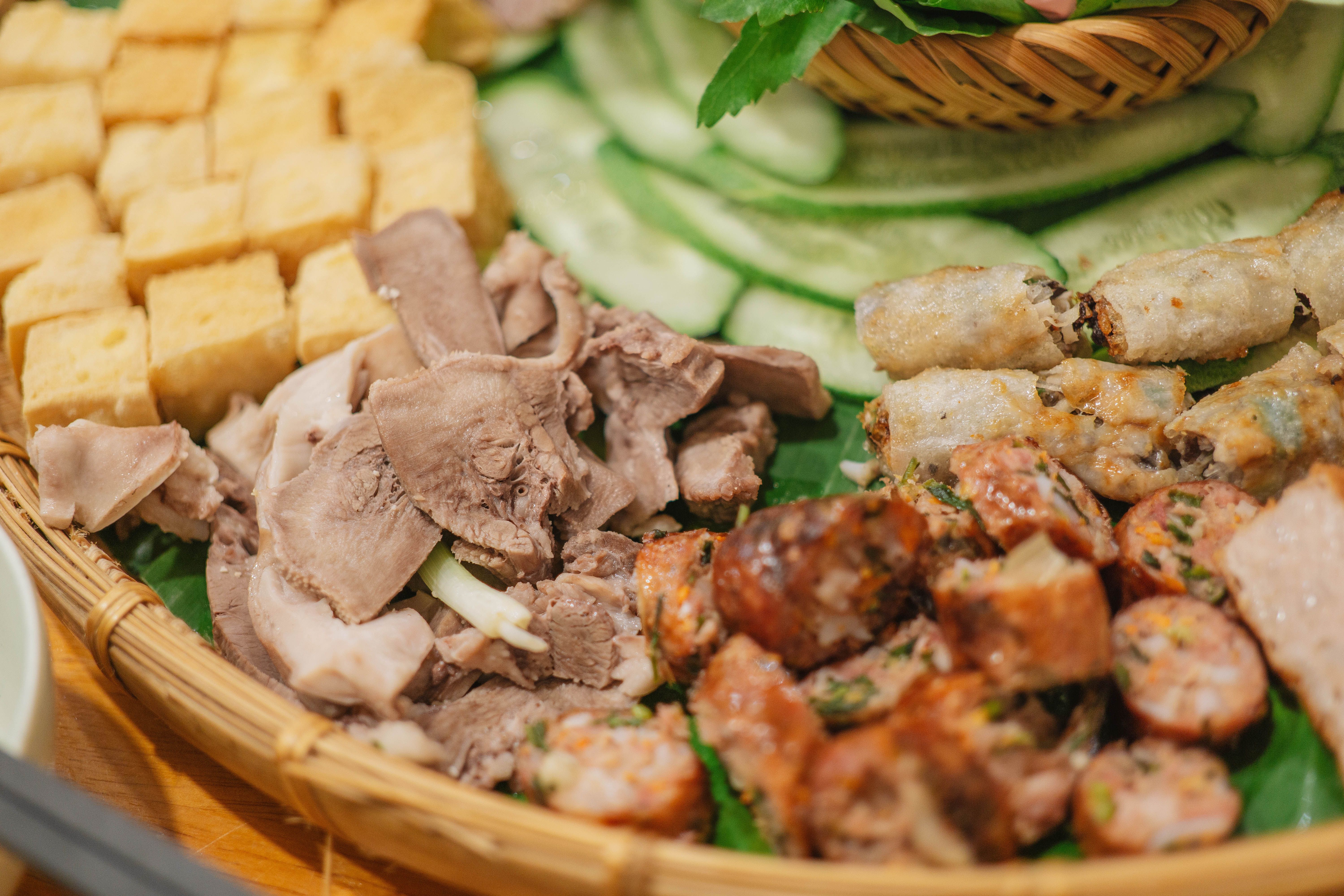 A vibrant Vietnamese food platter featuring traditional dishes like spring rolls and sausages.
