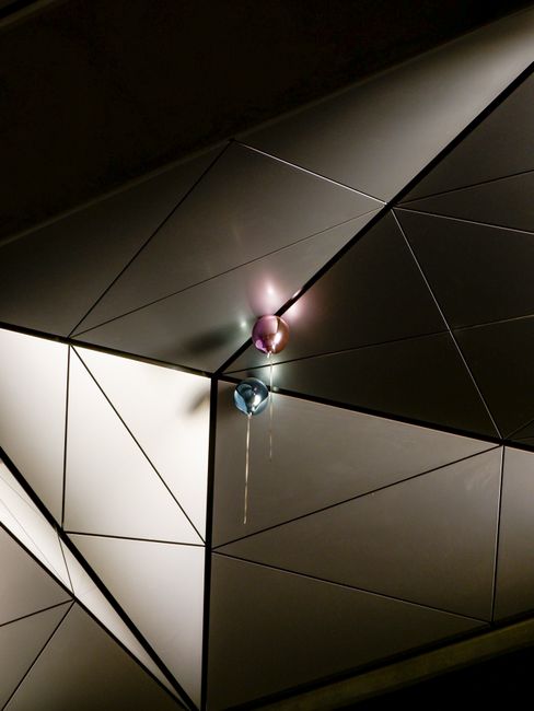 Modern geometric ceiling with colorful balloons, creating a playful contrast.