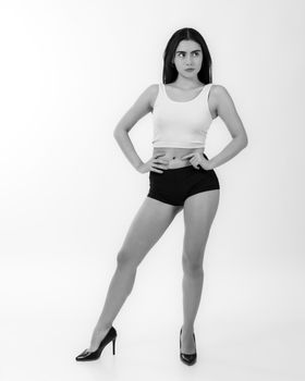 Stylish black and white portrait of a confident woman posing in a minimalist studio.