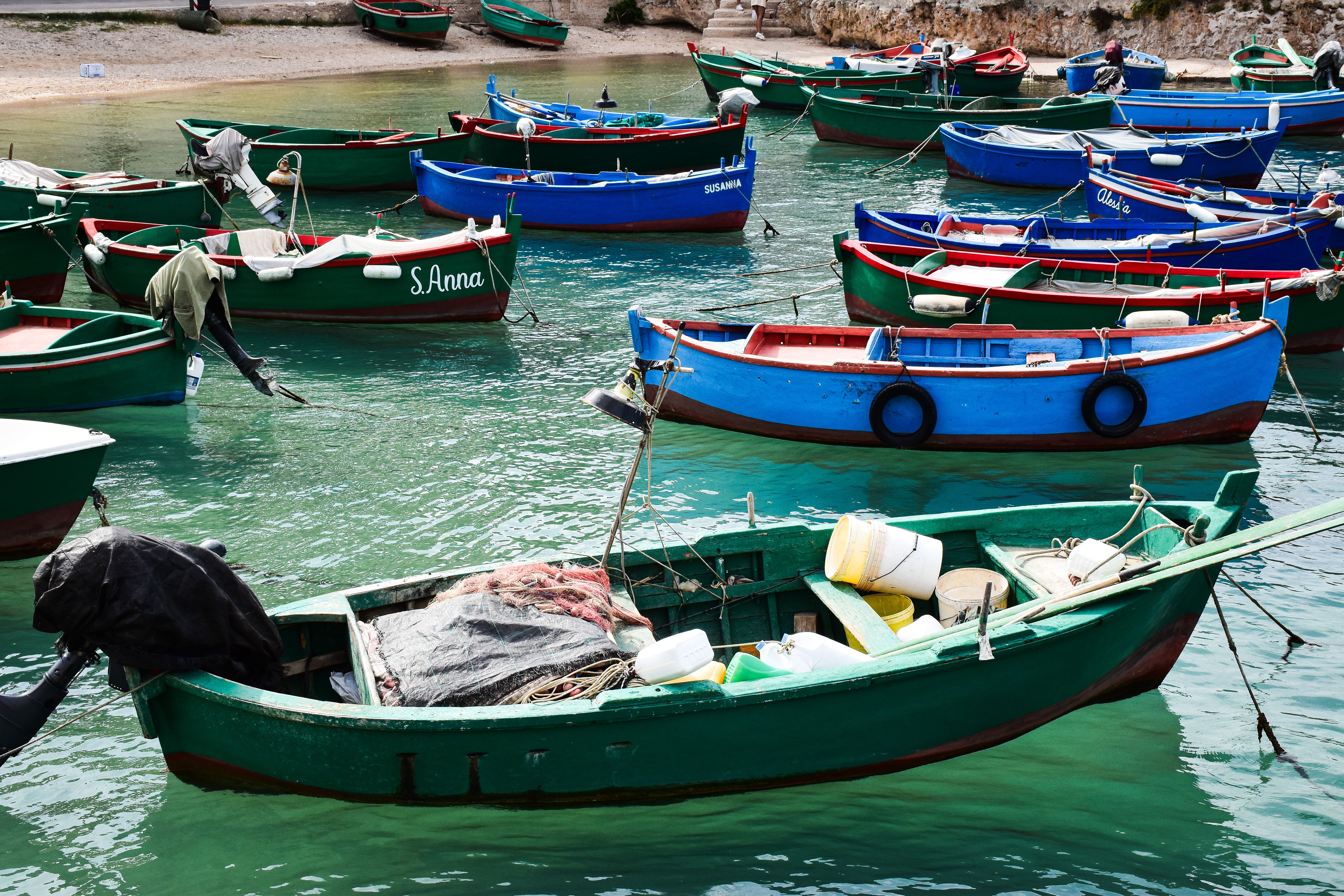 Colorful fishing boats in the scenic harbor of Polignano a Mare, Apulia, Italy.
