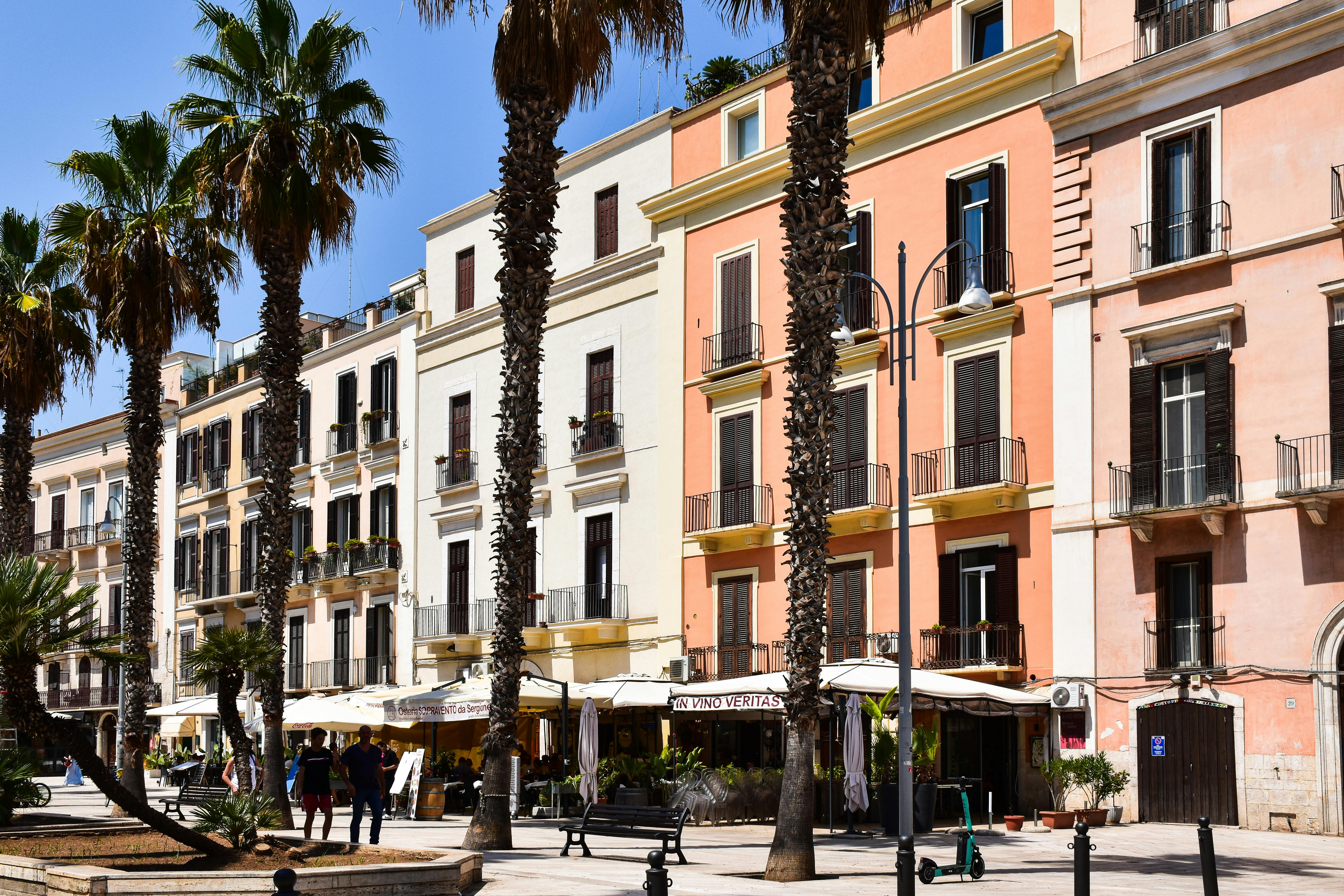 Colorful buildings and palm trees line a vibrant street in Bari, capturing the essence of Apulia.