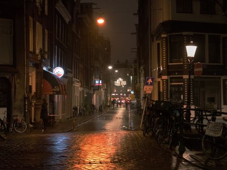 Atmospheric view of a dimly lit street in Amsterdam's old town, reflecting urban nightlife.