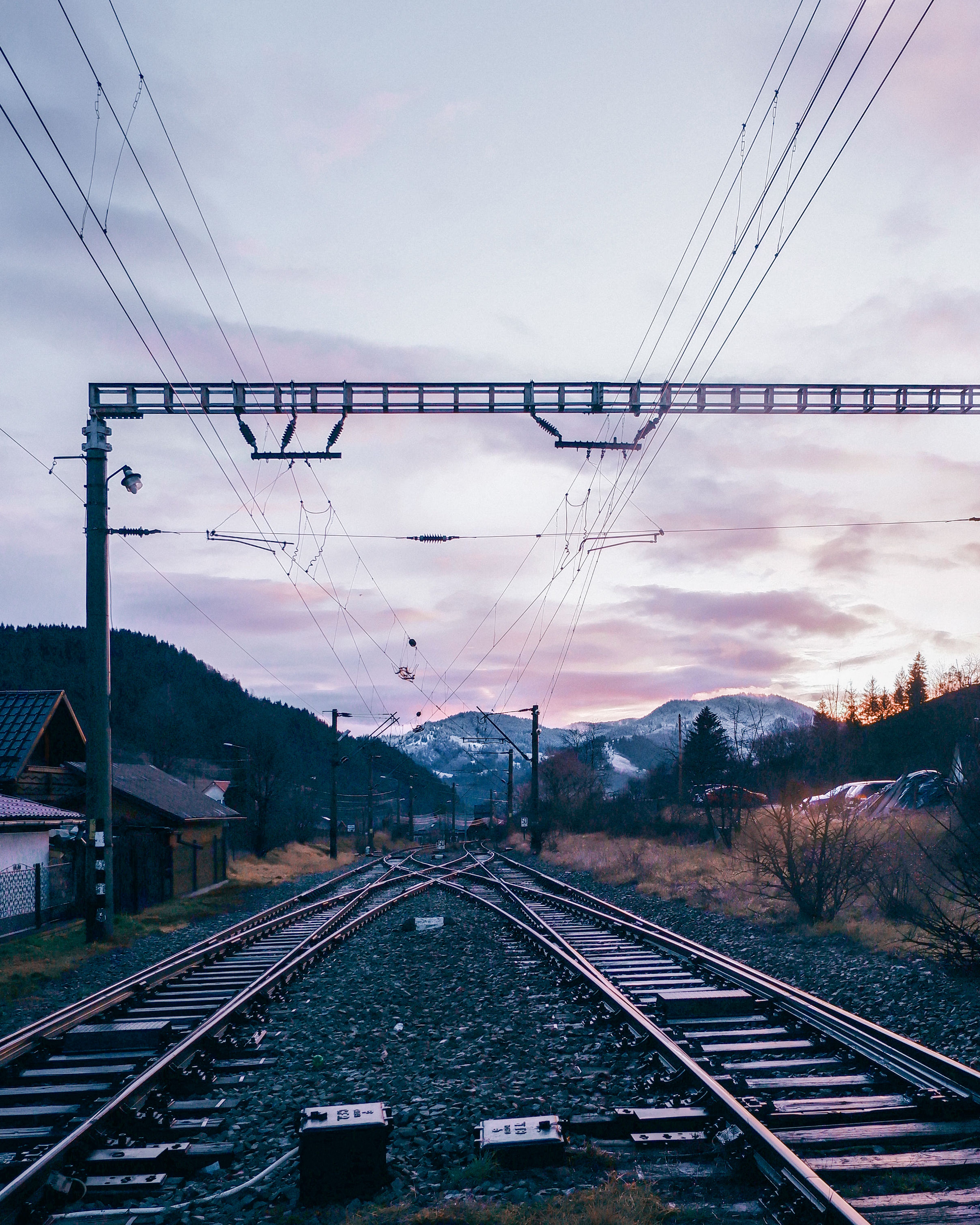Railway tracks at sunset in Romanian mountain landscape, showcasing serene beauty.
