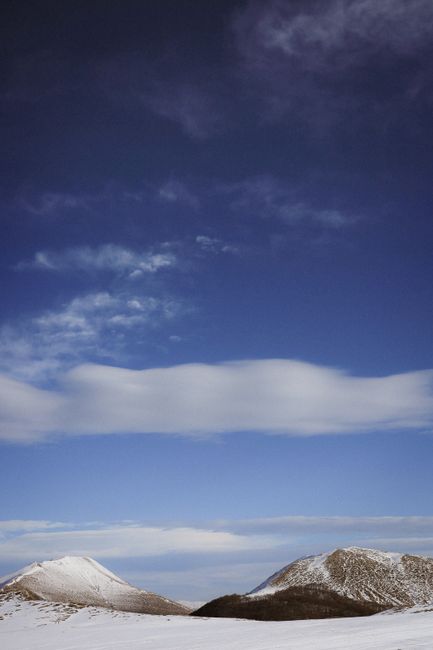 Snow-capped mountains beneath a vast, cloud-speckled blue sky.