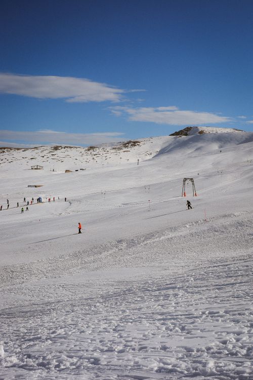Free A picturesque snowy mountain landscape with skiers enjoying a clear winter day under blue skies. Stock Photo