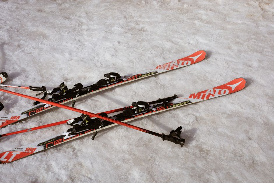 Red and black skis and poles resting on snow, suggesting a winter sports scene.