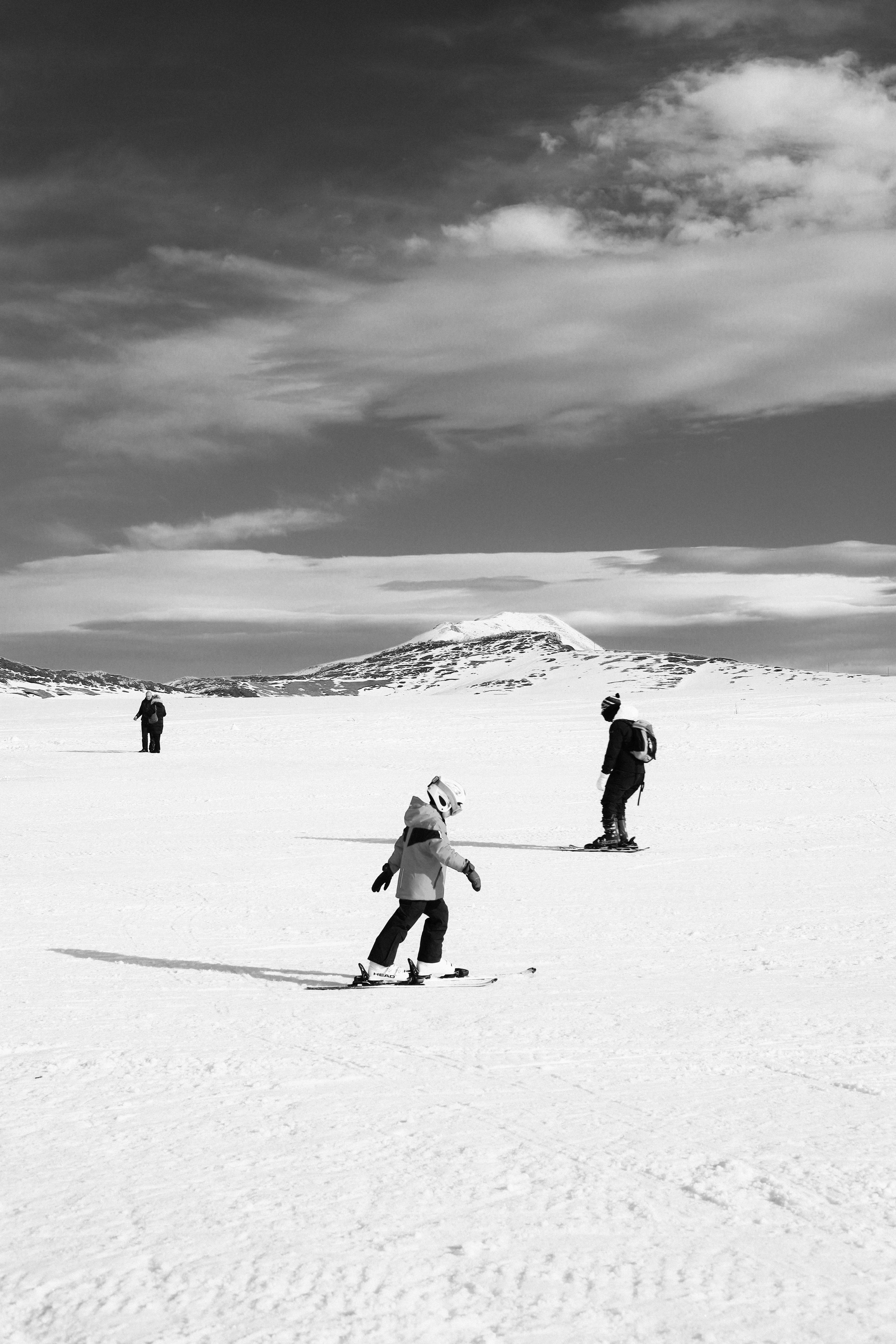 Monochrome photo of skiers enjoying a sunny day on a snowy mountain slope.