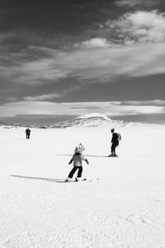 Monochrome photo of skiers enjoying a sunny day on a snowy mountain slope.