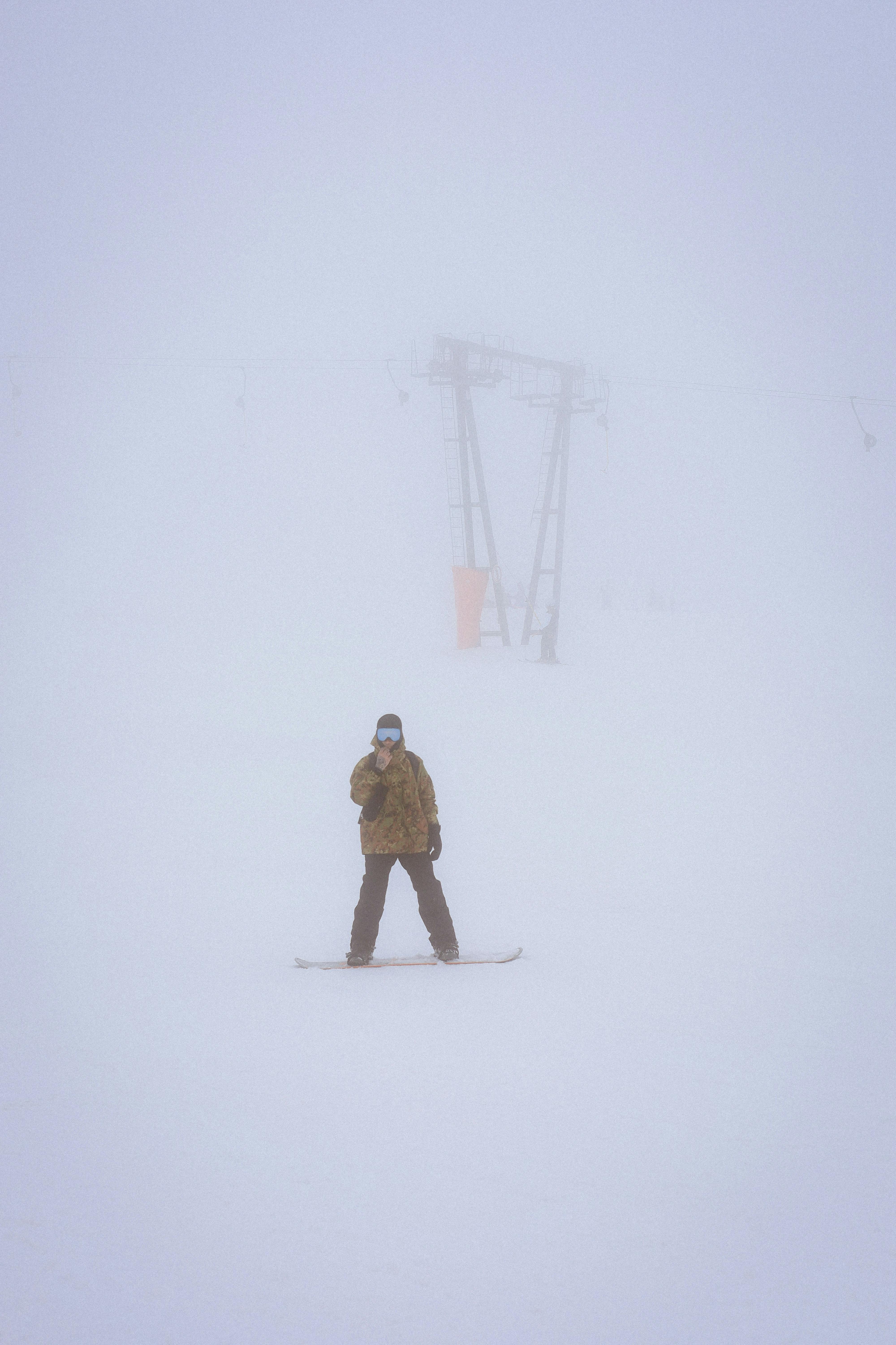 A solitary skier moves through a snow-covered, foggy winter landscape, creating a serene and mysterious ambiance.