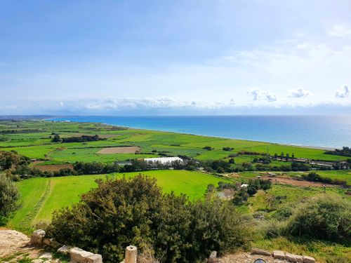 Free Vibrant coastal landscape featuring lush green fields and the clear blue sea under a bright sky. Stock Photo