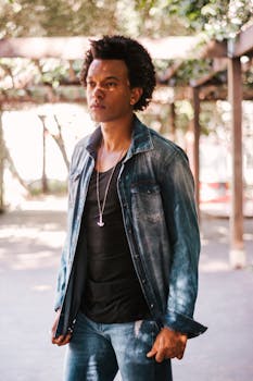 在圣保罗，一个穿着牛仔夹克的年轻人站在户外，风格休闲