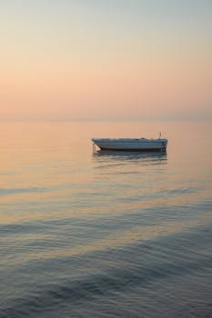 A serene boat floating on the calm sea during a beautiful sunset, capturing a sense of peace and tranquility.