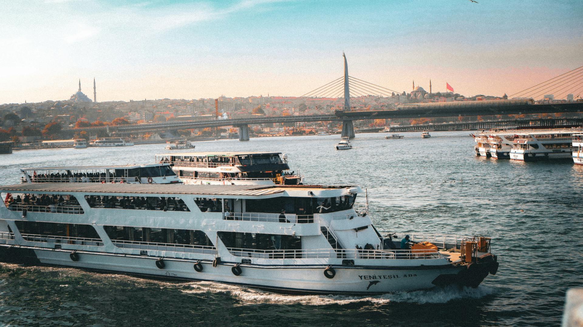 A ferry sails on the Bosphorus with the iconic Istanbul skyline and bridge in the background.