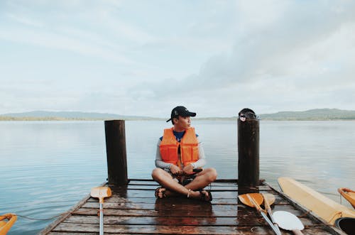 Man Wearing Life Vest While Sitting On The Dock