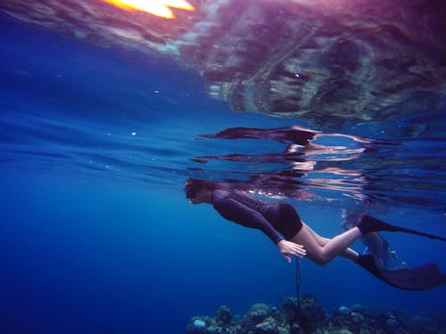 Frau In Der Tauchausrüstung, Die Unter Wasser Nahe Suface Schwimmt