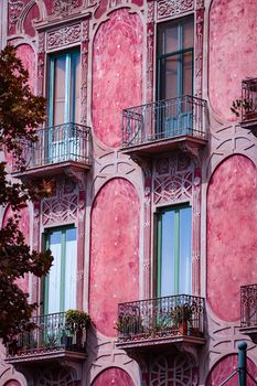 A classic Italian building facade in Catania, Sicily showcasing elegant balconies and rich pink tones.