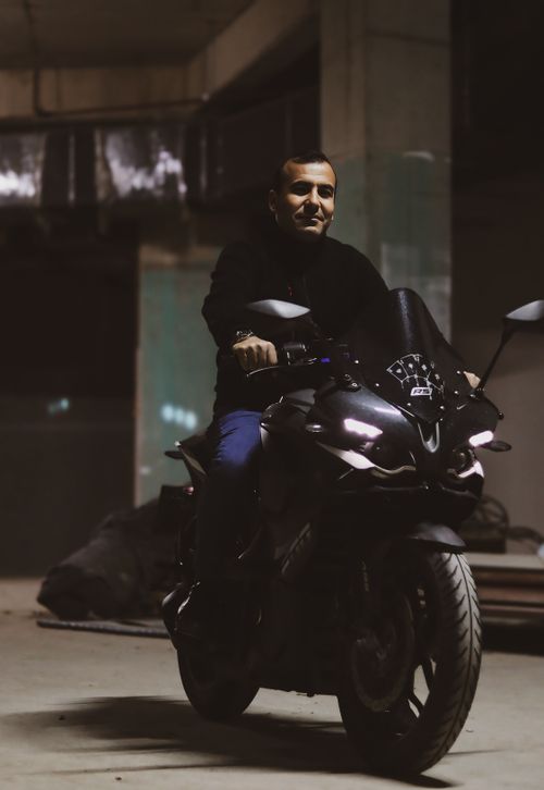 Free Man on a motorcycle in a dimly lit garage, capturing a moody and dramatic scene. Stock Photo