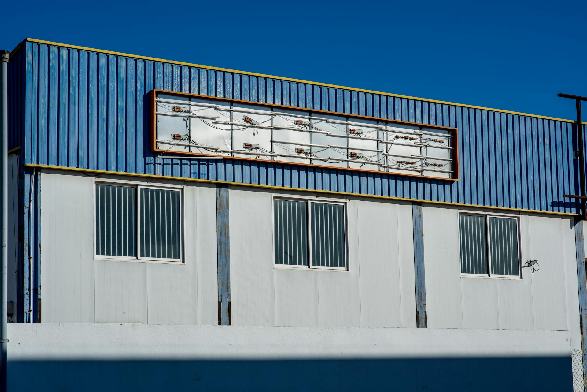 Exterior of a building with blue metallic facade and empty signage area.