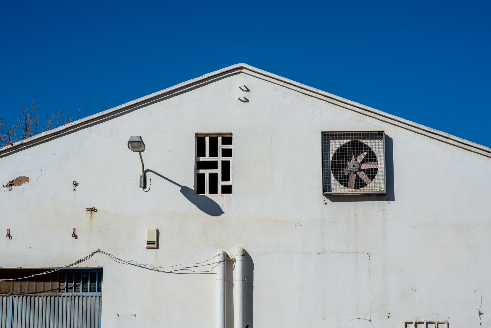 Exterior of industrial building with air vent and clear blue sky.