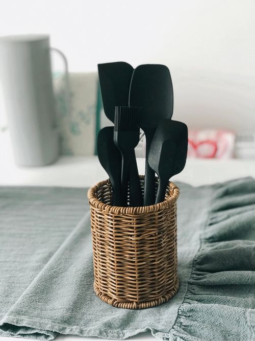 Free Black kitchen utensils in a wicker basket on a kitchen counter. Stock Photo