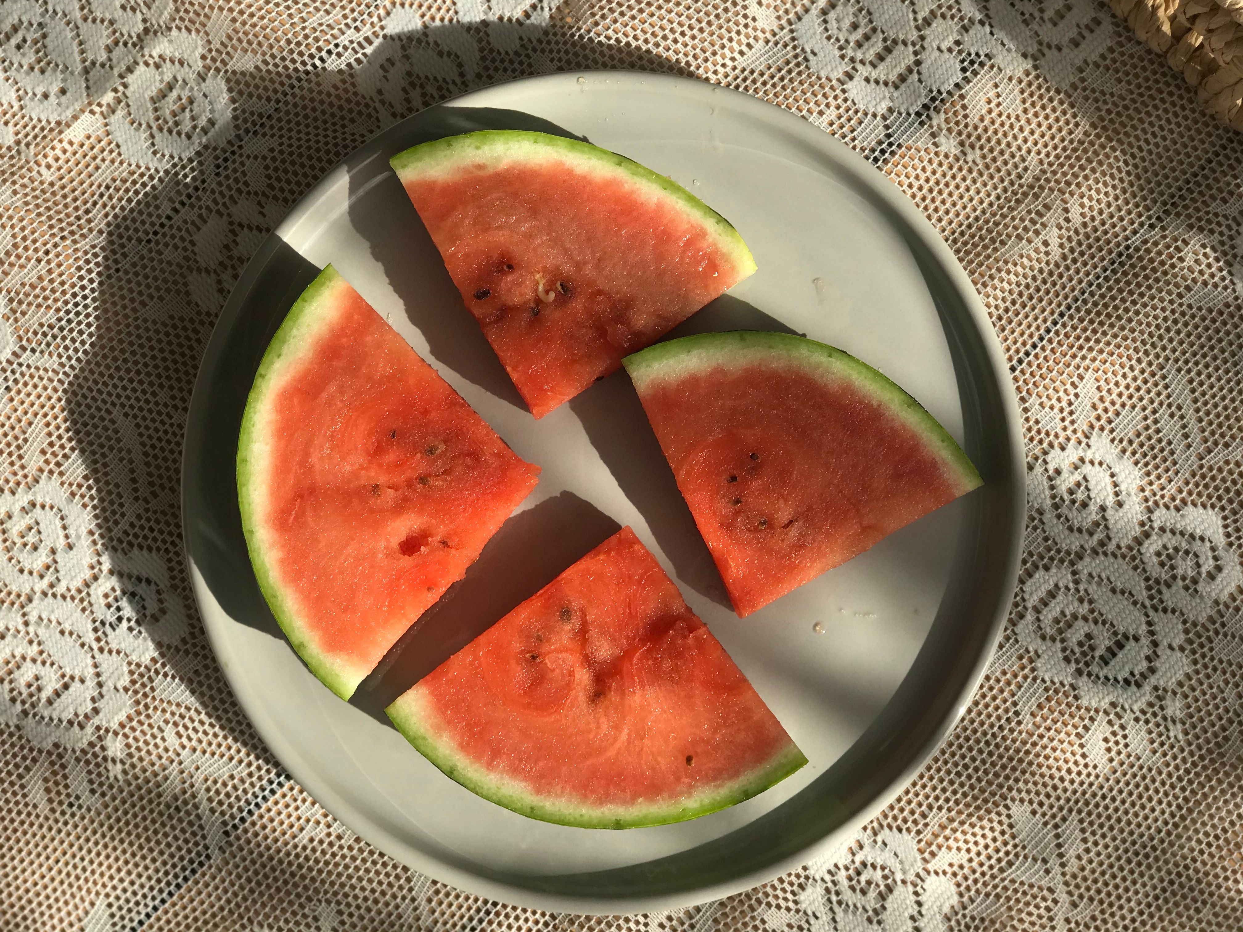 Top view of fresh watermelon slices on a decorative plate surrounded by lace tablecloth.