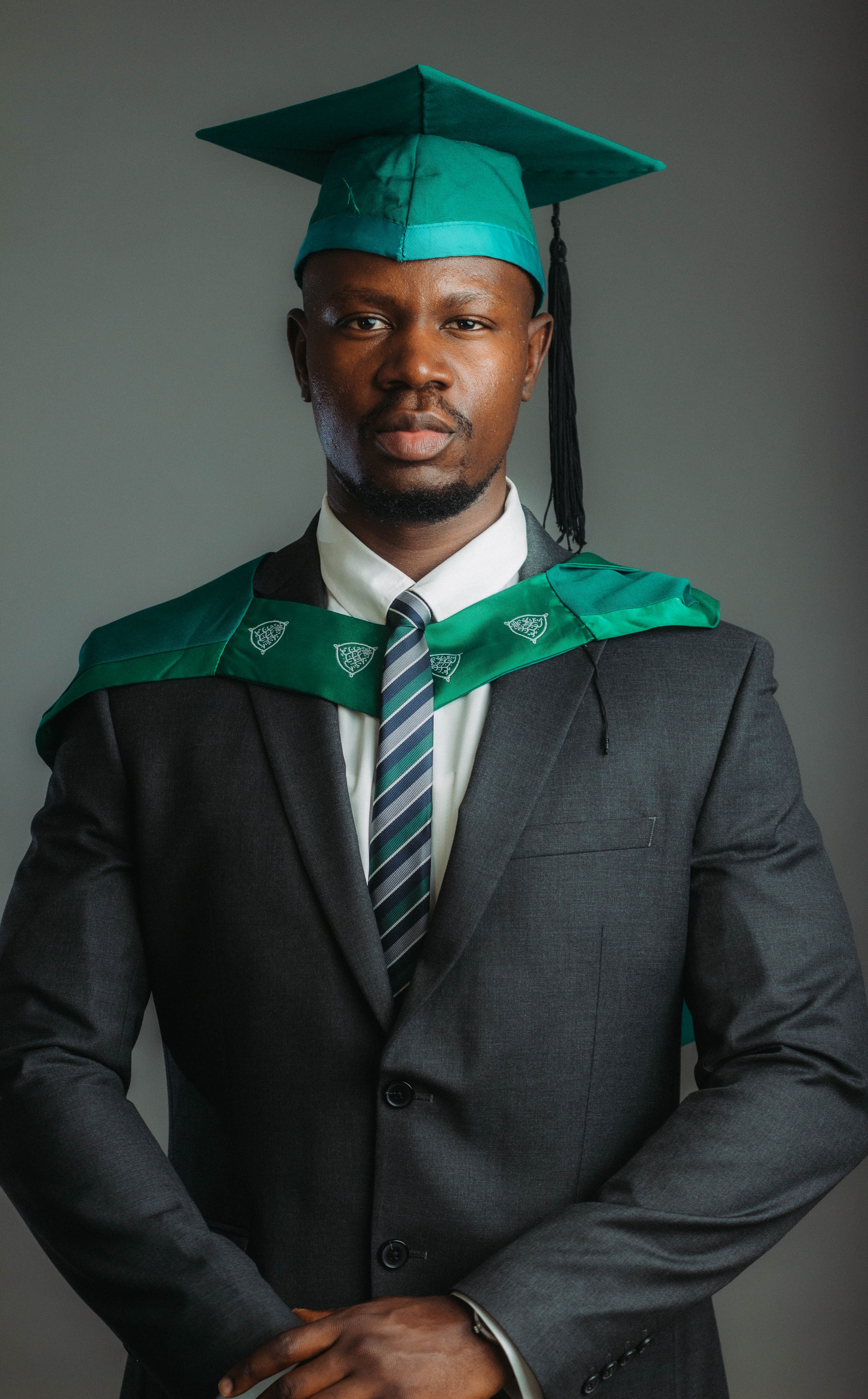 Confident male graduate in formal attire with cap and gown.