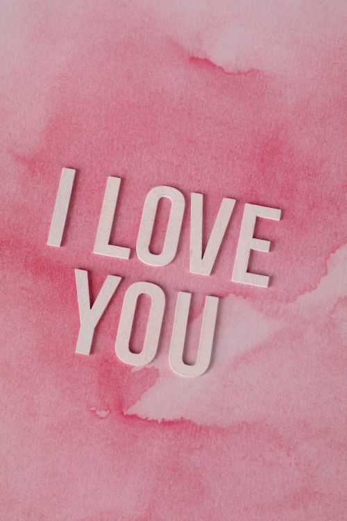 Free Artistic 'I Love You' text on pink watercolor background, perfect for romantic themes. Stock Photo