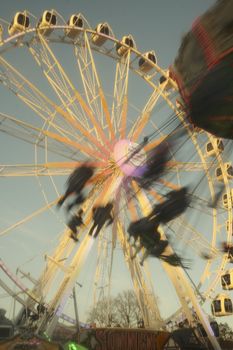 Dynamic motion blur of a vibrant ferris wheel with swinging seats at sunset.