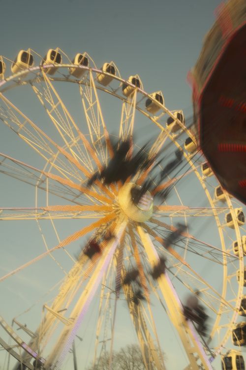Free Blurred motion capture of a spinning Ferris wheel during sunset at a lively carnival. Stock Photo