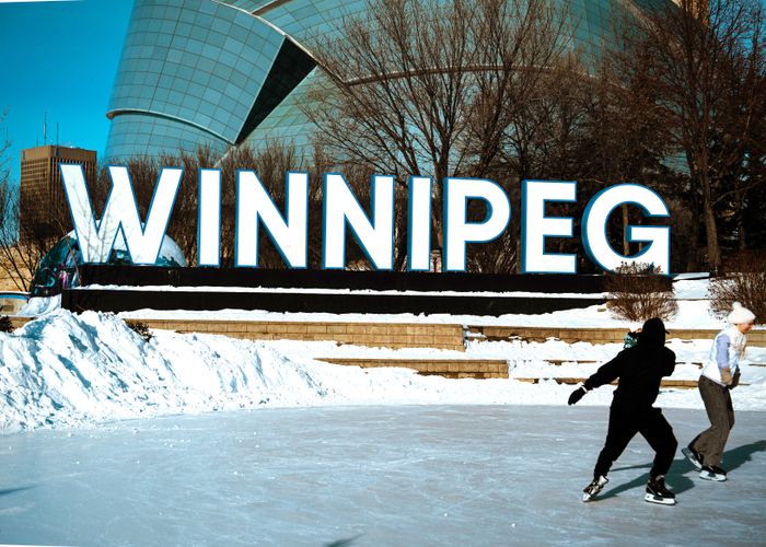 People ice skating in front of the Winnipeg sign during winter