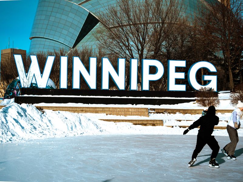 People ice skating in Winnipeg near the iconic Winnipeg sign in winter