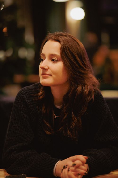 Free Thoughtful young woman sitting indoors, softly lit setting. Stock Photo
