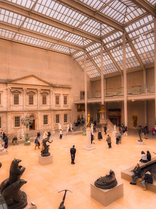 Free Visitors explore a spacious art museum gallery with historic architecture and sculptures. Stock Photo