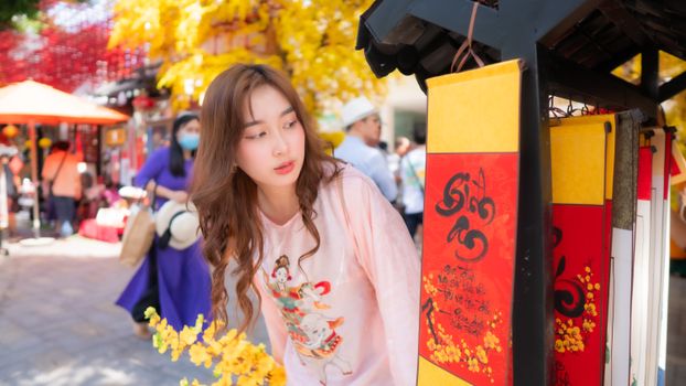 A young woman browsing a vibrant street market adorned with yellow flowers and traditional decorations.