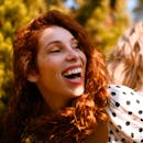 一幅充满活力的肖像画，描绘了一个快乐的红发女人在装饰着波尔卡圆点的户外环境中大笑