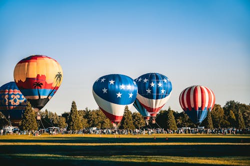 Free Anchored Hot Air Balloons at Field Full Of People Stock Photo