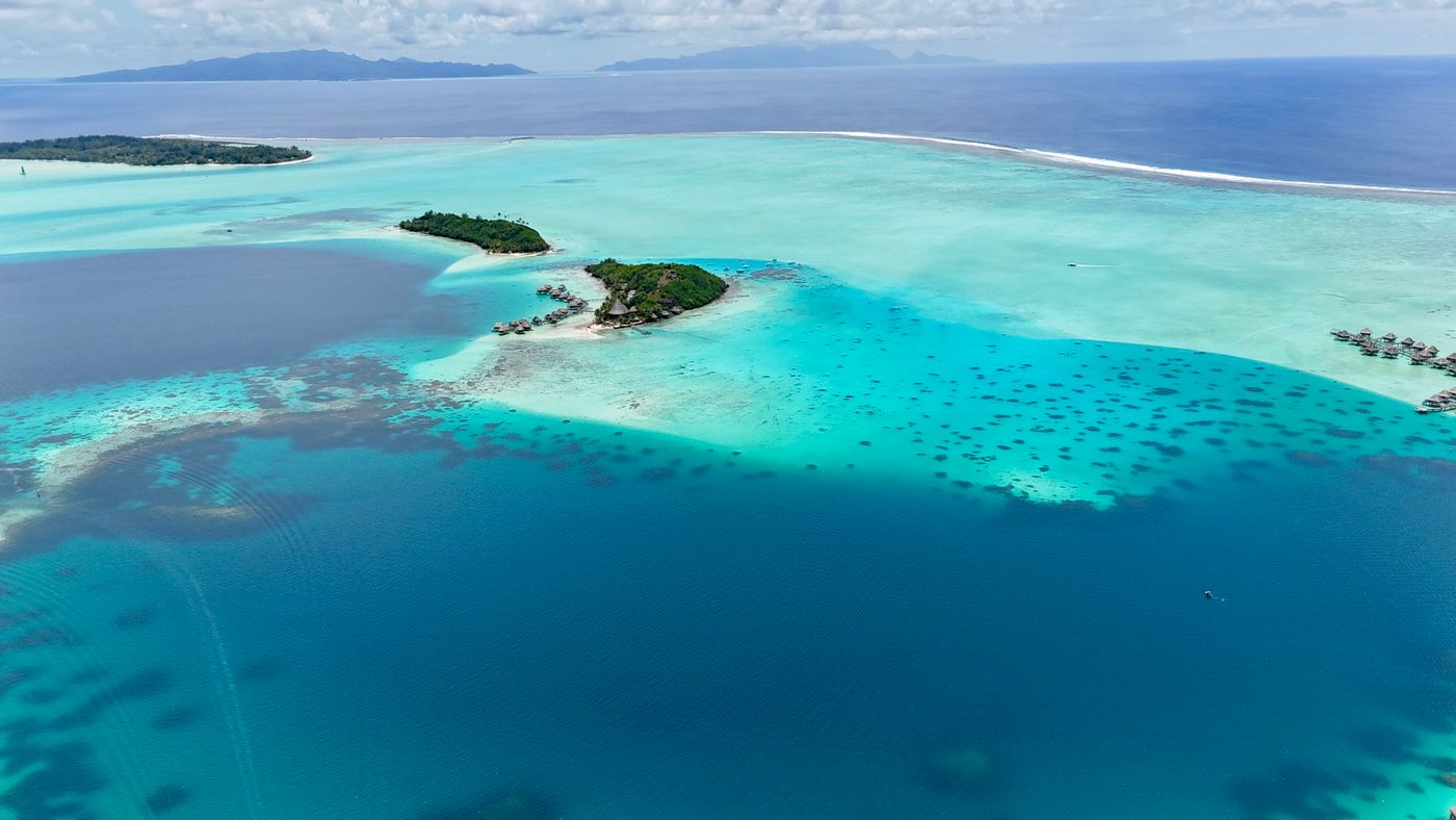 Aerial view of the turquoise lagoon and green motu of Bora Bora, French Polynesia