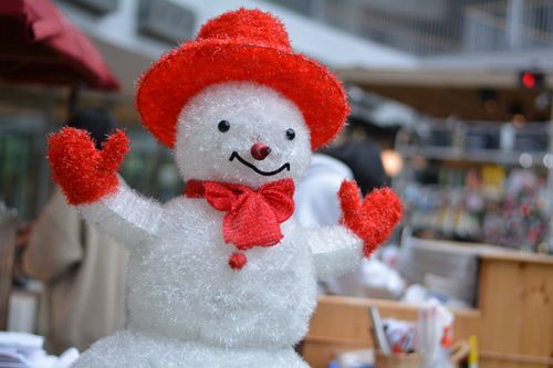 Free Cheerful snowman in red hat and gloves spreading holiday joy indoors. Stock Photo